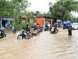 Air Hujan Meluap ke Jalan, Anggota Kodim 0802 Bantu Tertibkan Lalu lintas dan Seberangkan Warga yang Melintas