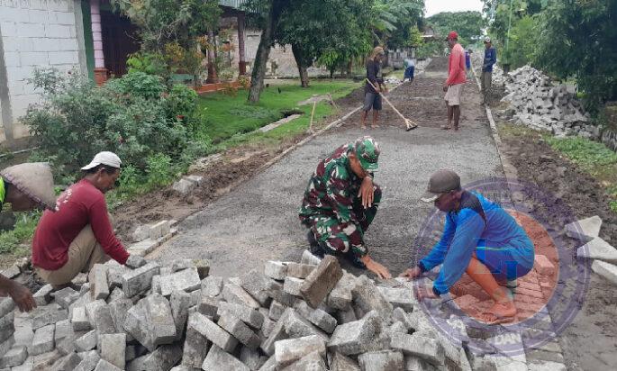 Bersama Warga, Serda Arif Gotong Royong Pasang Paving