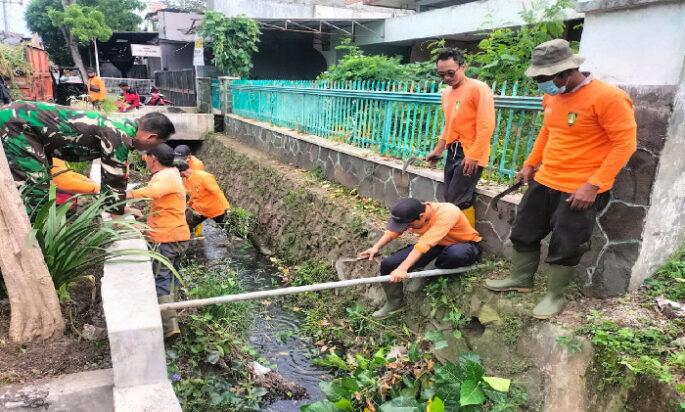 Gandeng Saberling Babinsa Purwosari Bersihkan Rumput Liar yang Merambat di Pagar dan Saluran Air